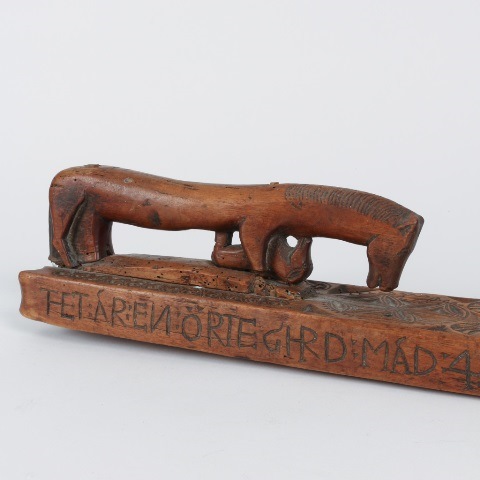 Detail of an archaic Swedish mangle board with the unusual presence of a foal carved under the horse-shaped handle, dated 1731