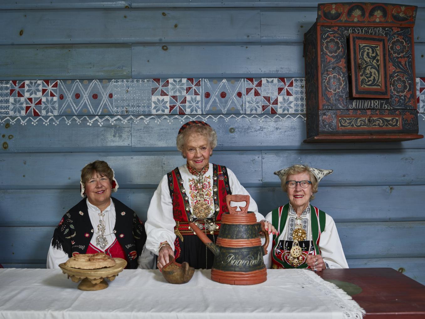 American Women in traditional Norwegian clothing examine a loom at Vesterheim